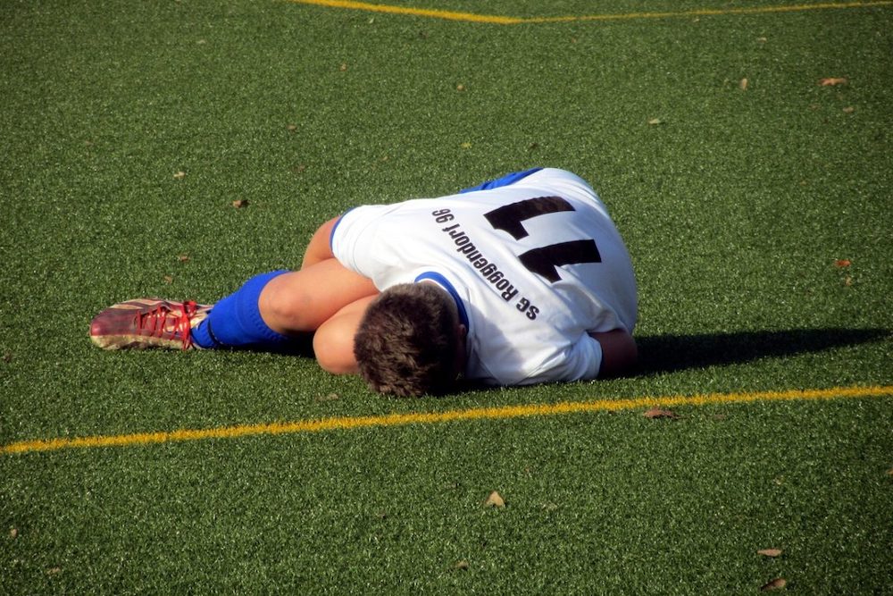 Soccer player laying on turf grabbing knee
