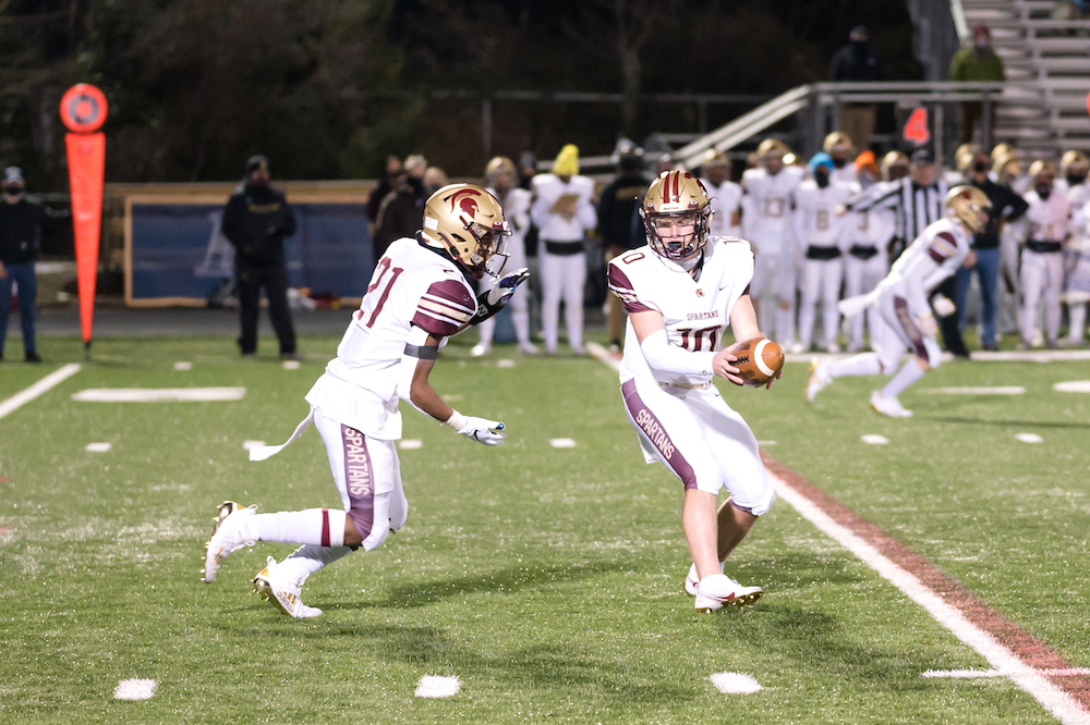 Brett Griffis of Broad Run Football hands the ball off to Kyle Davis during the Spartans' win at Loudoun County on February 23 in Leesburg